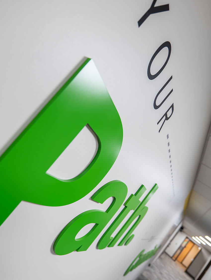 Green Path letters on a wall in a modern corridor, emphasizing direction and progress.