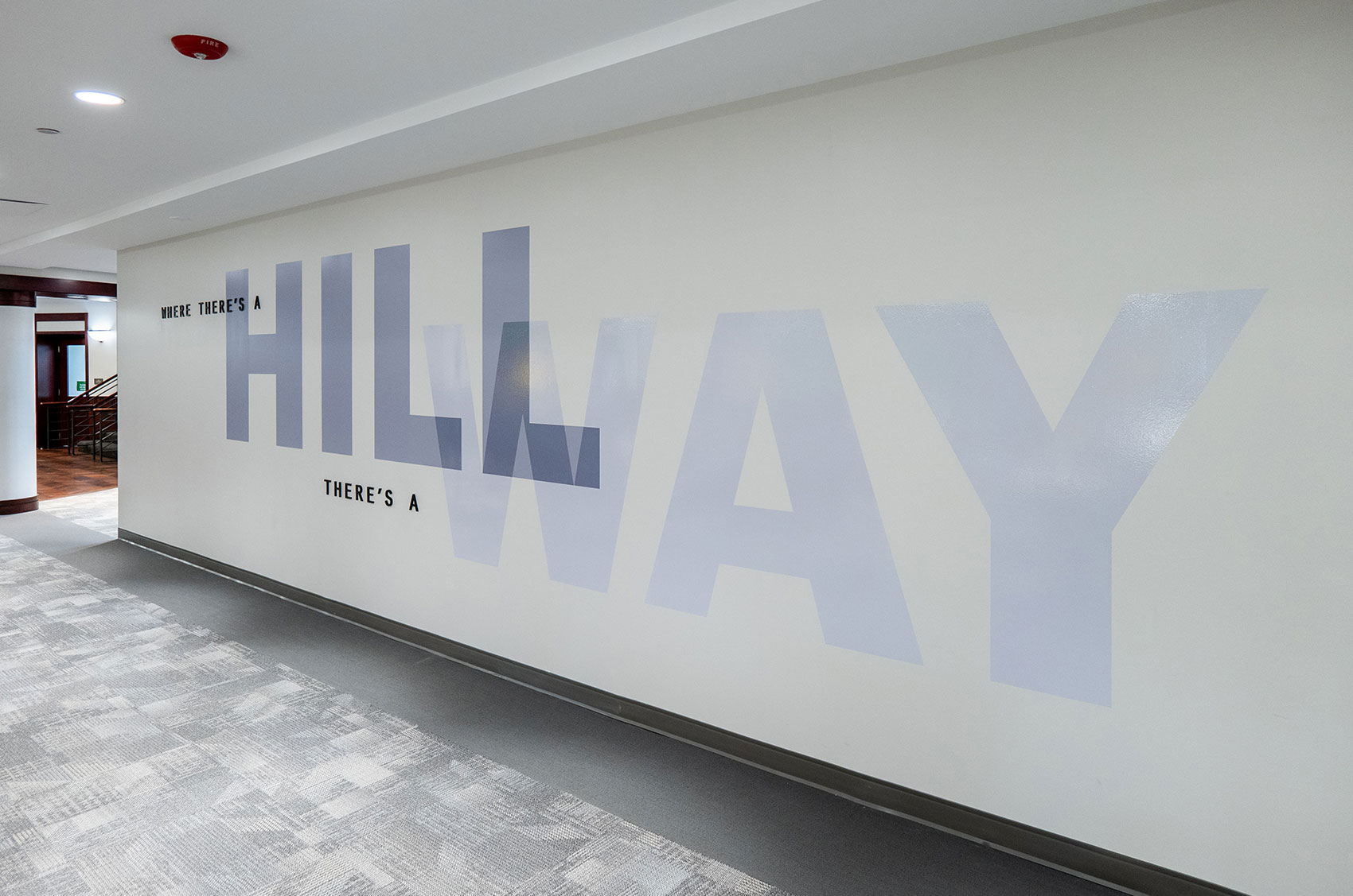 Hallway with motivational slogan Where there's a Hill, there's a Way on the wall in modern office space.